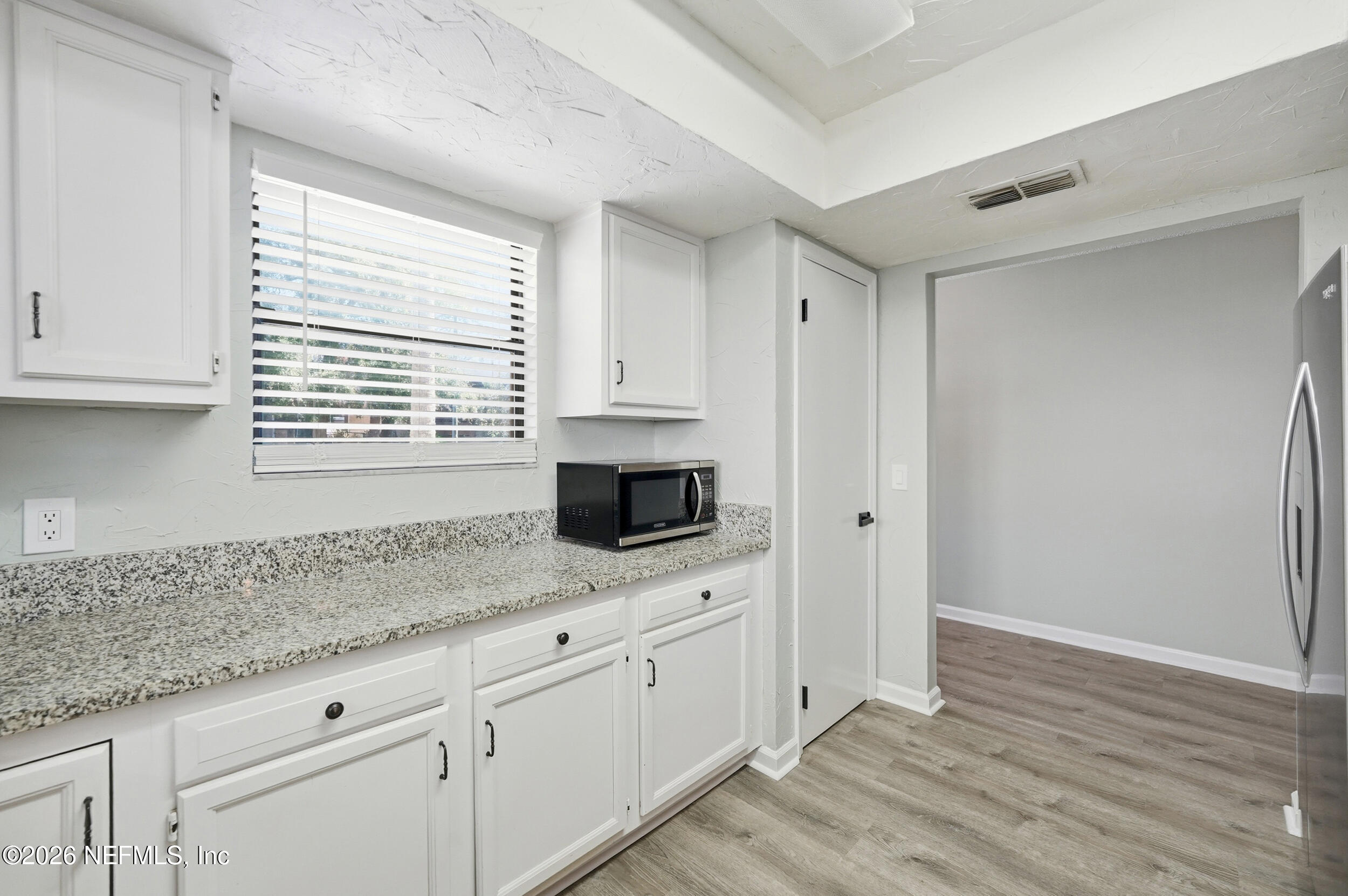 144 Poinsettia Street Atlantic Beach, FL 32233 - Photo 21 of 42 a kitchen with granite countertop white cabinets and window