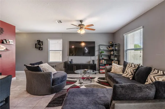 a living room with furniture ceiling fan and a flat screen tv