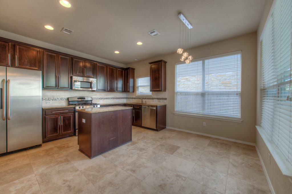 11204 Old Quarry Road Austin, TX 78717 - Photo 8 of 18 Rich wood cabinetry and tile flooring define this open kitchen and dining space.