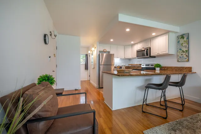 a kitchen with granite countertop white cabinets and a stove a oven with wooden floor