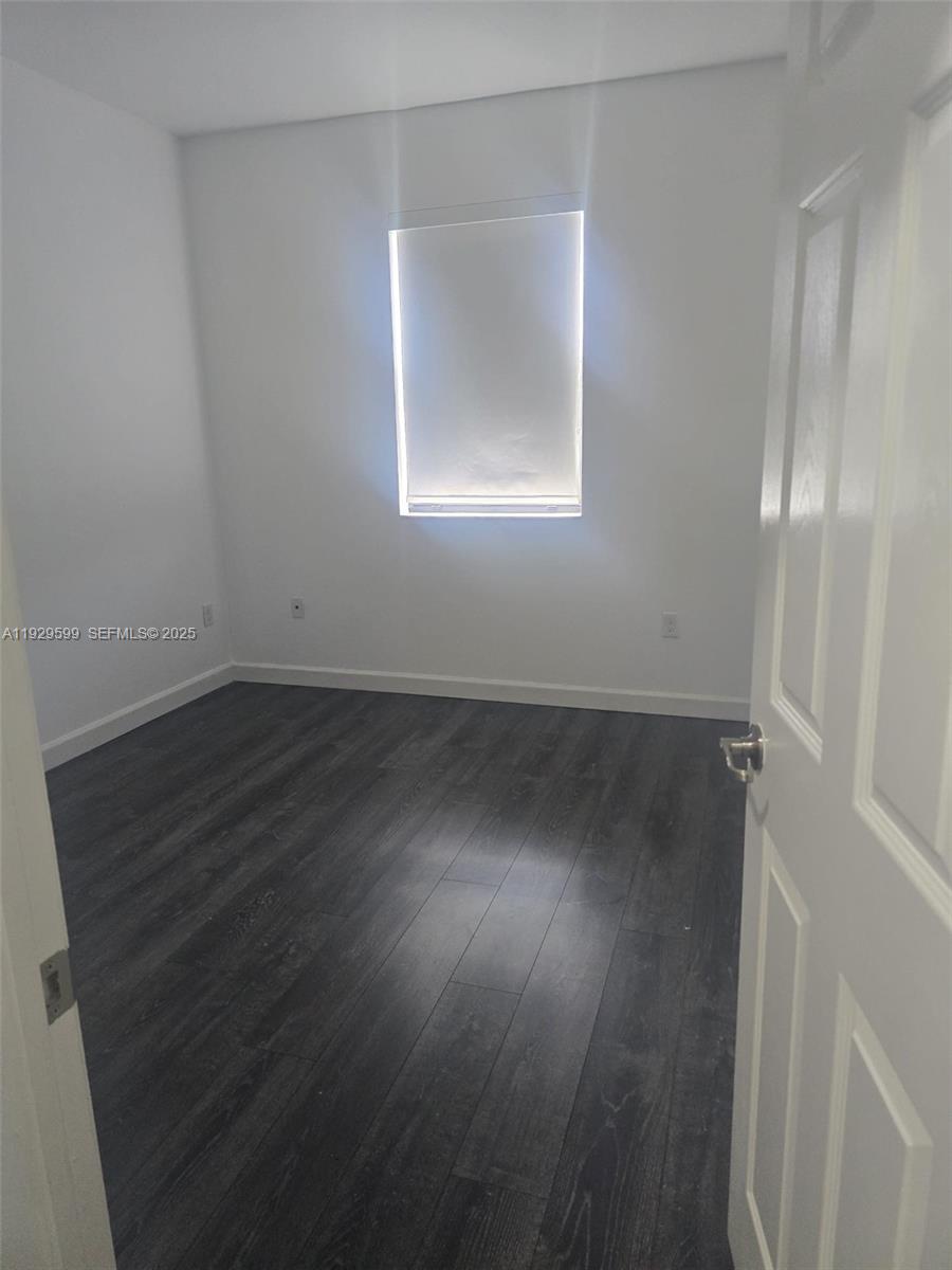 3399 West 90th Terrace Hialeah, FL 33018 - Photo 11 of 59 an empty room with wooden floor and windows