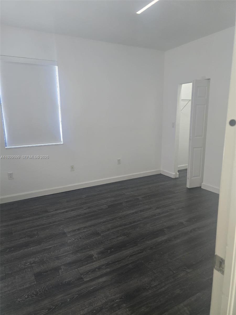 3399 West 90th Terrace Hialeah, FL 33018 - Photo 17 of 59 a view of an empty room with wooden floor and a window
