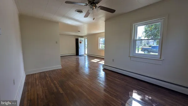 a view of an empty room with wooden floor and a window