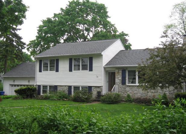 a view of a house with a yard potted plants and a large tree