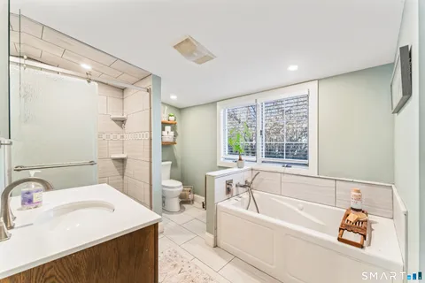 a bathroom with a bathtub a sink a mirror and a shower