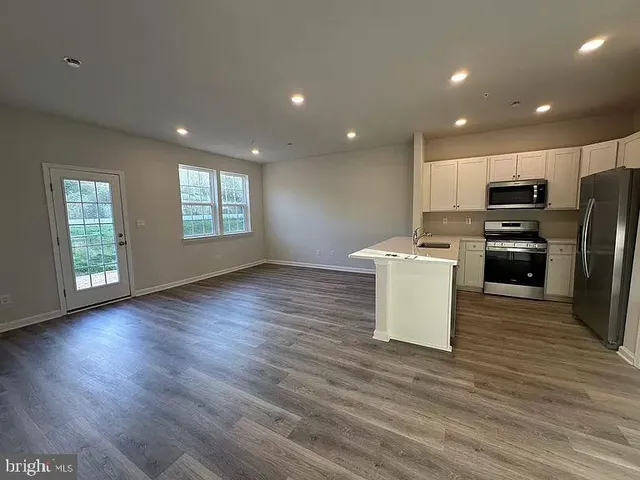 a view of a kitchen with a sink dishwasher oven and wooden floor