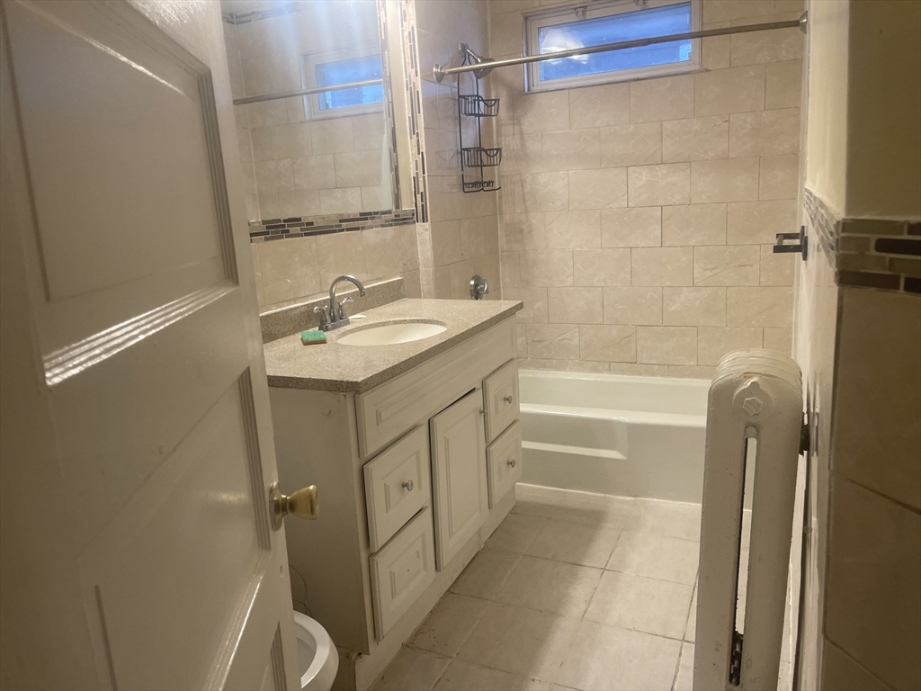 6 Bailey Street, Unit 1 Boston, MA 02124 - Photo 11 of 12 a bathroom with a granite countertop sink a toilet and shower