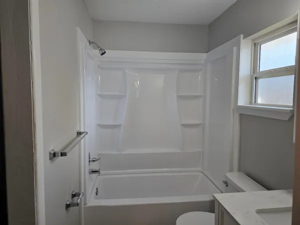 a bathroom with a bathtub shower and toilet