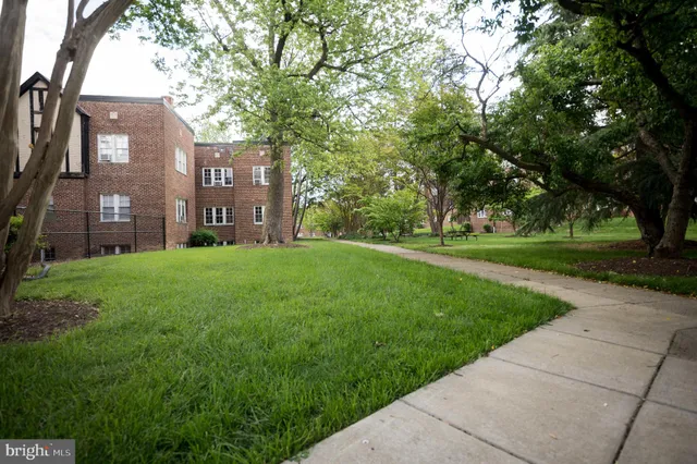 a view of a brick house with a big yard and large trees