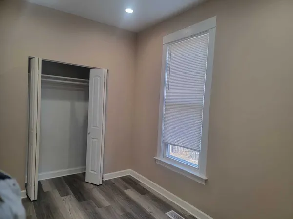 a view of an empty room with wooden floor and closet