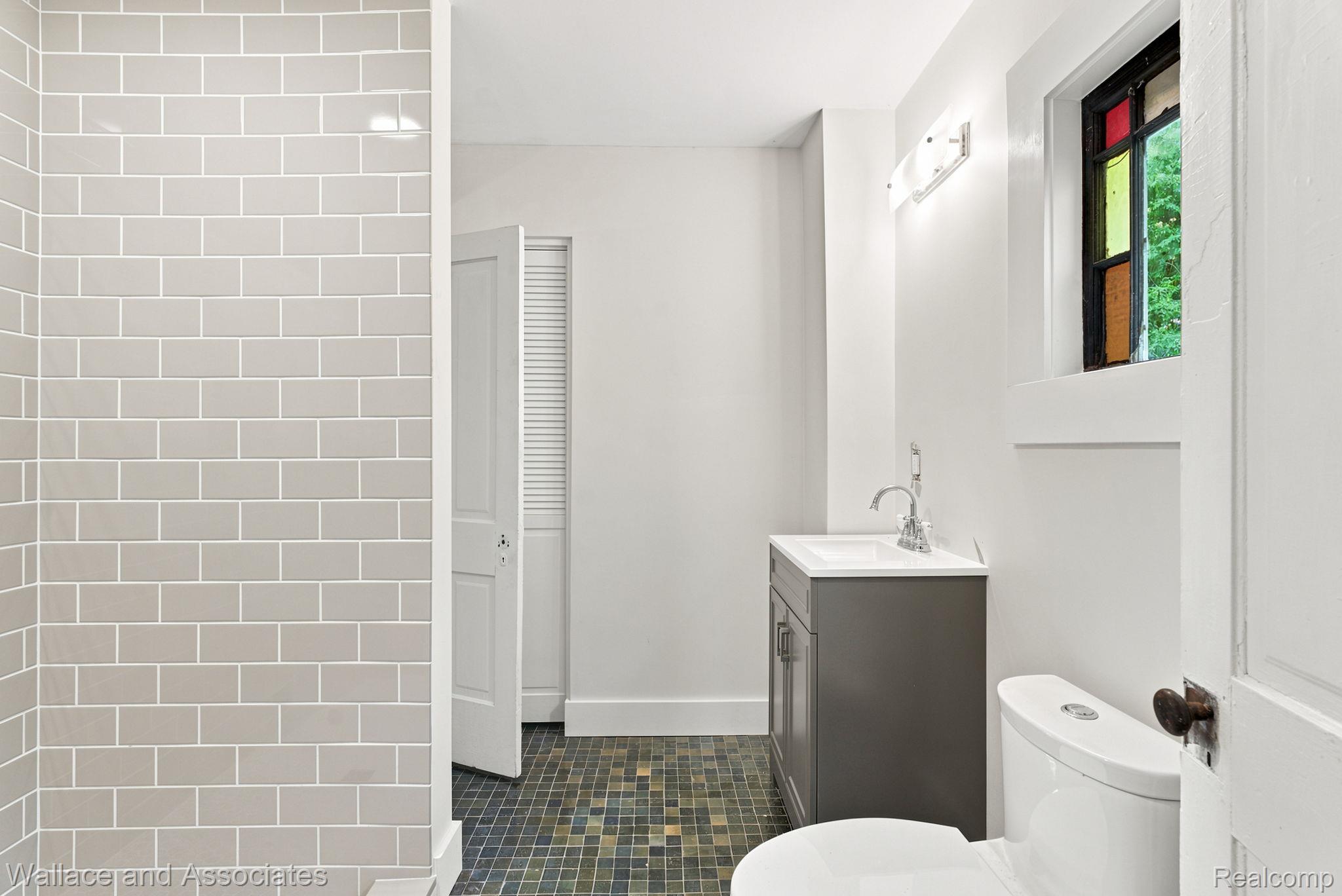 5949 Roach Road Croswell, MI 48422 - Photo 28 of 48 Bathroom featuring subway tile shower surround, mosaic floor tiling, vanity with integrated sink, and an accent window with stained glass elements