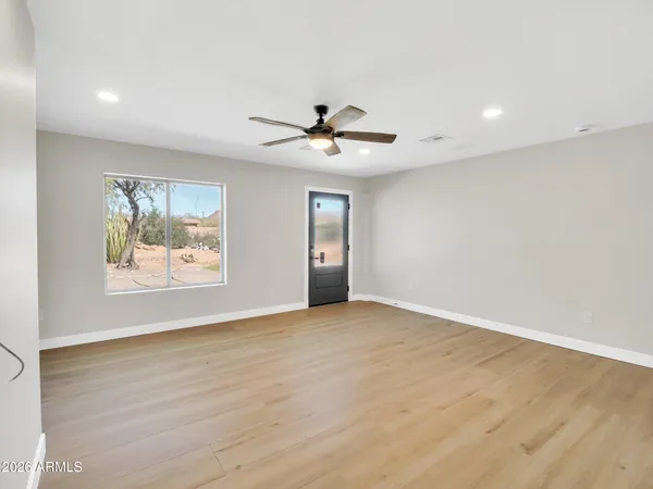 an empty room with chandelier fan and windows