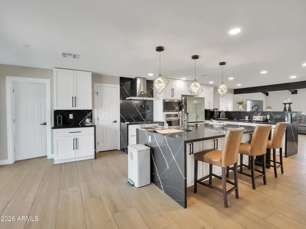 a kitchen with stainless steel appliances kitchen island granite countertop a table chairs sink and cabinets