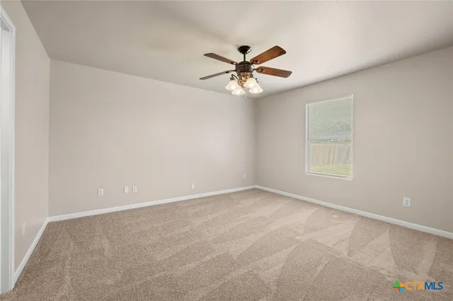 an empty room with a window and a fan