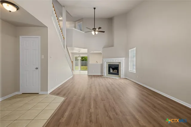 an empty room with wooden floor fireplace and hallway