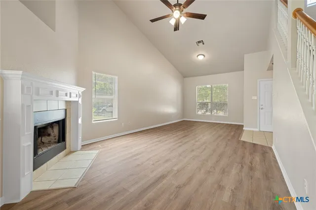 a view of an empty room with wooden floor fireplace and a window
