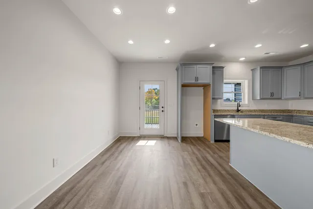 an empty room with wooden floor and a kitchen
