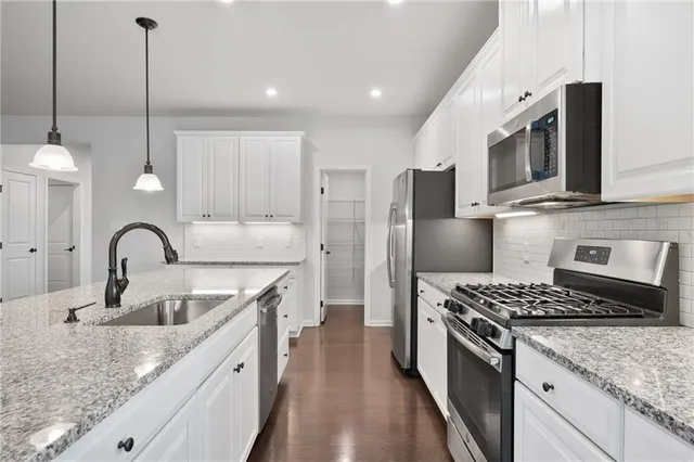 a kitchen with stainless steel appliances granite countertop a sink stove a refrigerator and cabinets