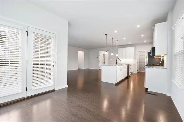 a living room with stainless steel appliances kitchen island hardwood floor and a large window