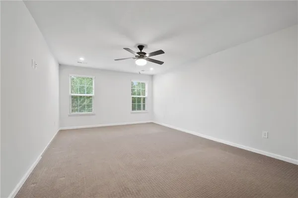 an empty room with windows and ceiling fan