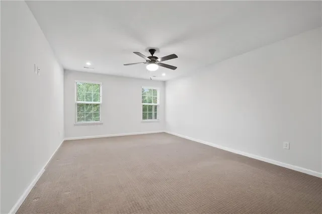 an empty room with windows and ceiling fan