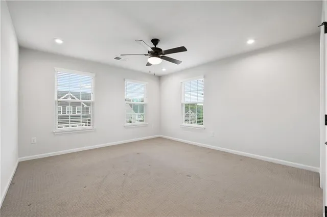 an empty room with windows and ceiling fan
