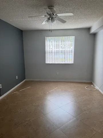 en empty room with windows and chandelier fan