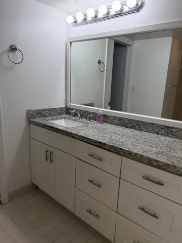 a bathroom with a granite countertop sink and mirror