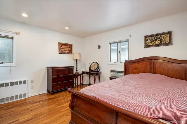 a bedroom with a bed and a dresser with wooden floor