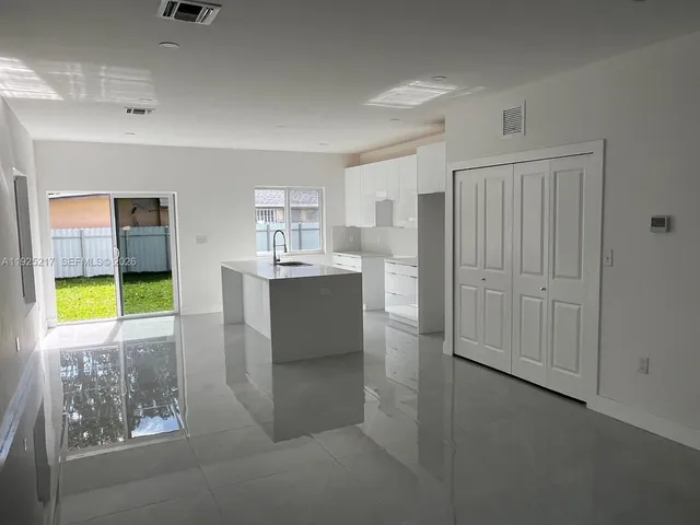 a room with kitchen island a sink a cabinets and window