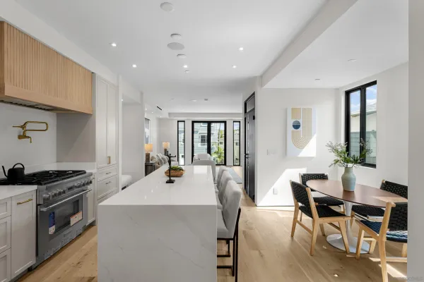 a kitchen with a stove a refrigerator and white cabinets with wooden floor