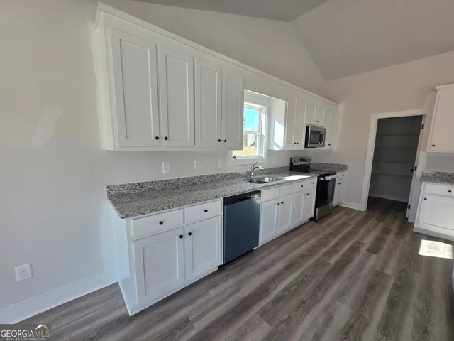 a kitchen with granite countertop a sink cabinets stainless steel appliances and a window