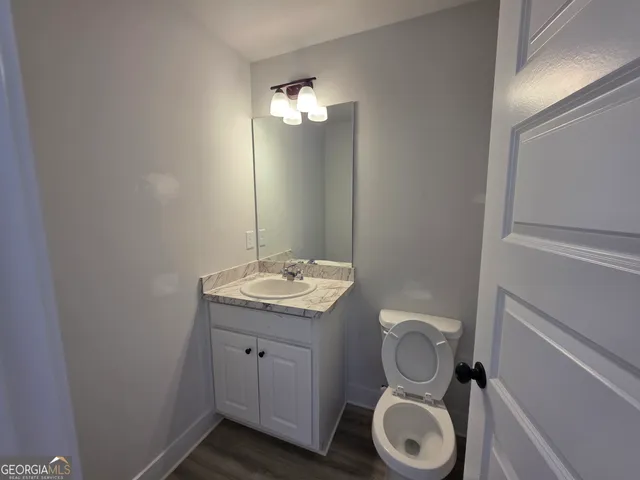 a bathroom with a granite countertop toilet a sink and a mirror