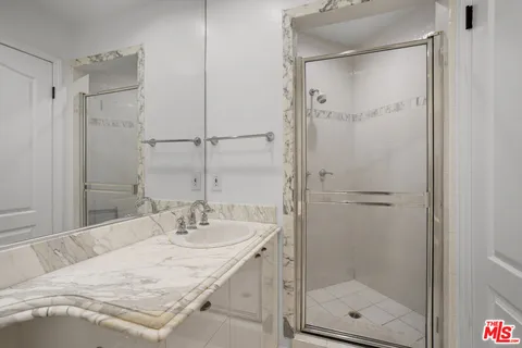 a bathroom with a granite countertop sink mirror and shower