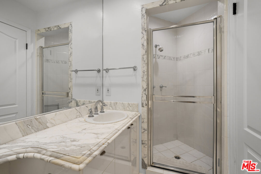 435 Arnaz Drive, Unit 304 Los Angeles, CA 90048 - Photo 16 of 21 a bathroom with a granite countertop sink mirror and shower