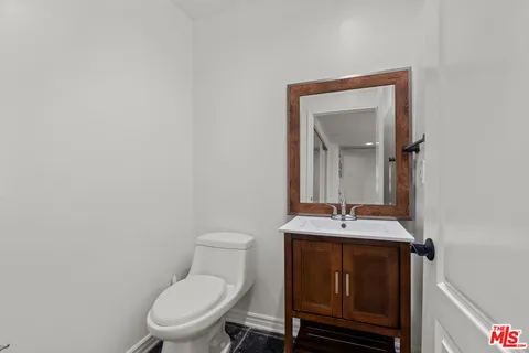 a bathroom with a toilet sink vanity and mirror