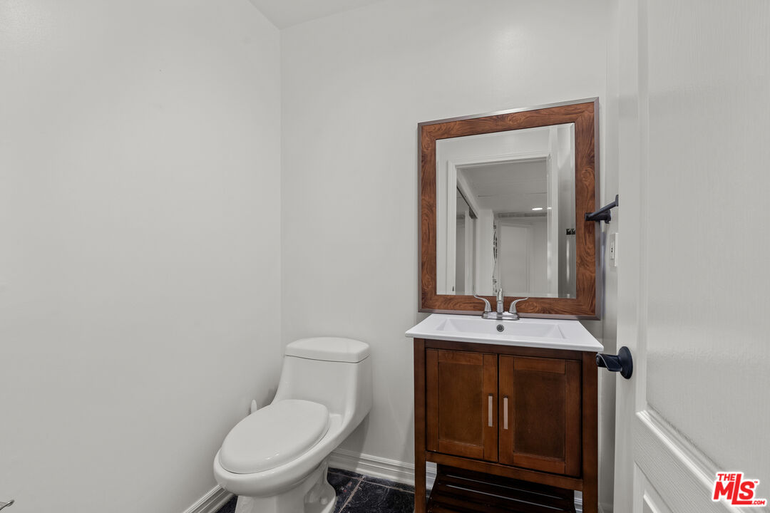 435 Arnaz Drive, Unit 304 Los Angeles, CA 90048 - Photo 17 of 21 a bathroom with a toilet sink vanity and mirror
