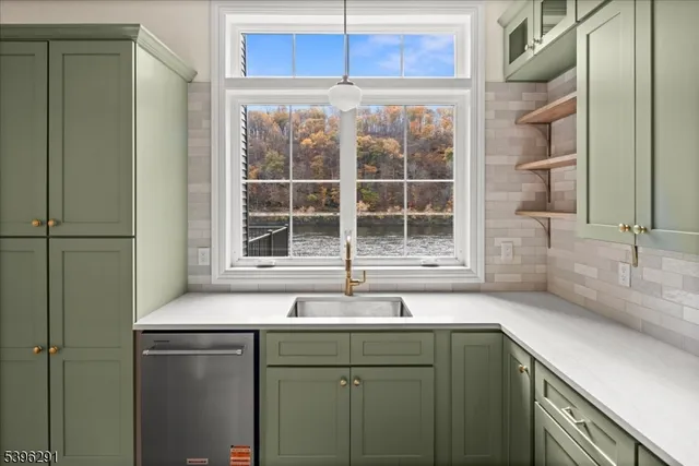 a large kitchen with a large counter top a sink stainless steel appliances and cabinets