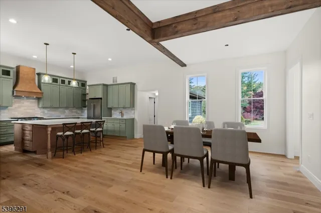 a large white kitchen with wooden floor and stainless steel appliances