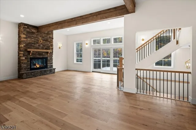 an empty room with wooden floor fireplace and windows