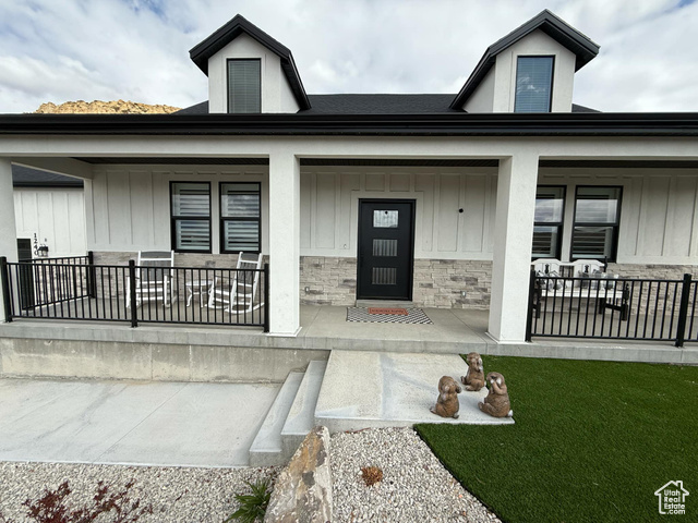 1240 West 2360 North Helper, UT 84526 - Photo 4 of 79 Entrance to property with covered porch, stone siding, board and batten siding, and a lawn