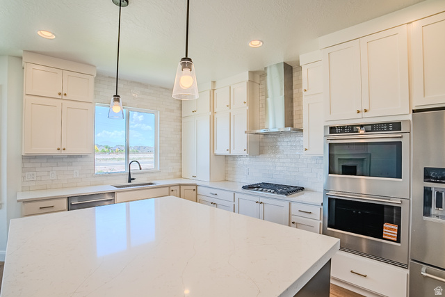 45 North Scarlet Maple Road, Unit 4317 Vineyard, UT 84059 - Photo 9 of 35 Modern kitchen featuring a spacious island with a light-toned countertop, white cabinetry with gold-toned hardware, stainless steel appliances including a built-in double oven and refrigerator, and a white subway tile backsplash