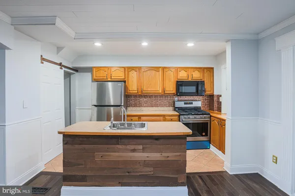 a view of kitchen island with stainless steel appliances wooden floor and large window