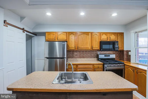 a kitchen with stainless steel appliances granite countertop a refrigerator a oven a sink dishwasher and wooden cabinets with wooden floor