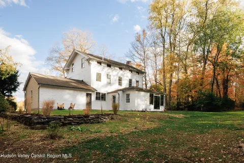 a view of a white house with a big yard and large trees