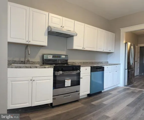 a kitchen with granite countertop white cabinets and stainless steel appliances