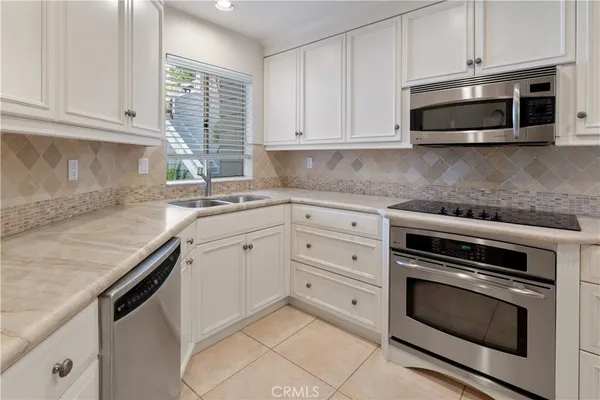 a kitchen with granite countertop white cabinets and stainless steel appliances