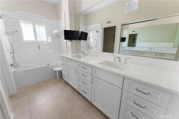 a spacious bathroom with a double vanity sink a mirror and a bathtub