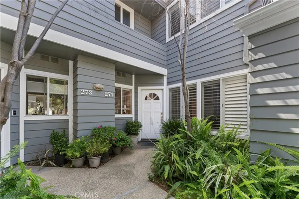 a view of a house with potted plants and a bench