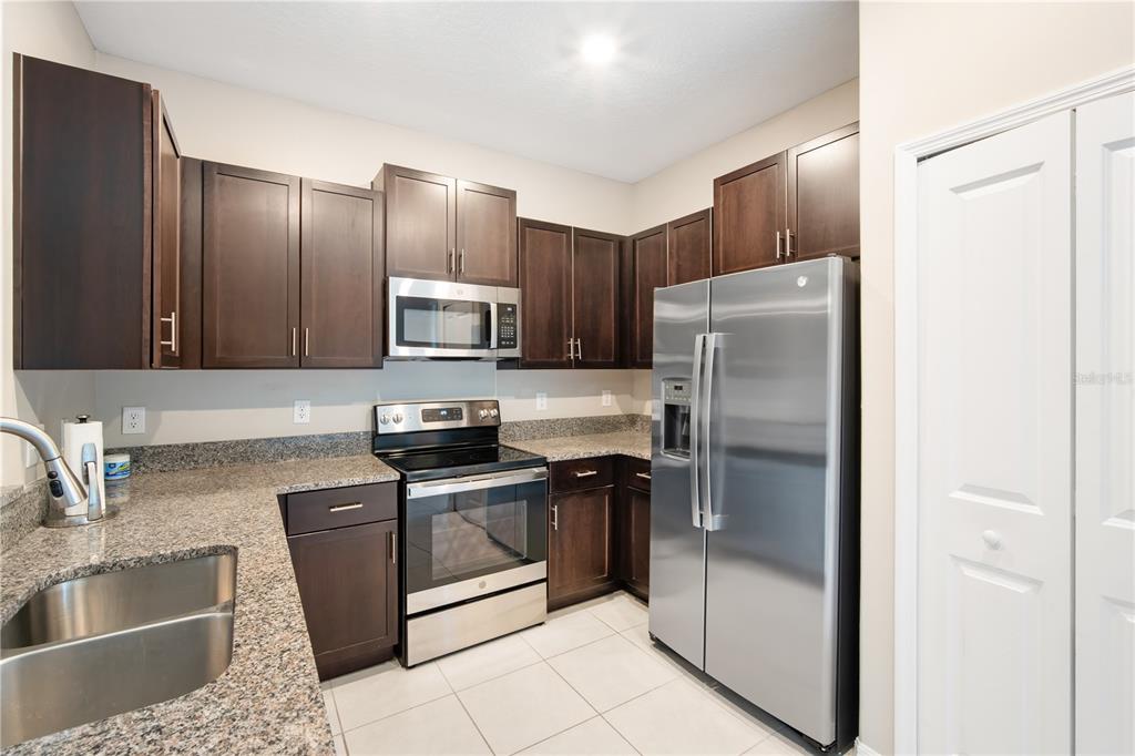 14316 Easy Goer Street Sun City Center, FL 33573 - Photo 5 of 26 a kitchen with granite countertop a refrigerator and a sink